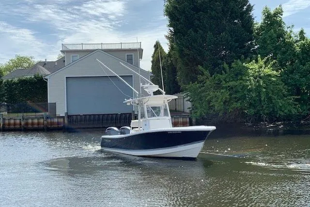 Slide: The Image of 2006 Regulator 24 Classic boat on a calm river near a boathouse and trees. - 28