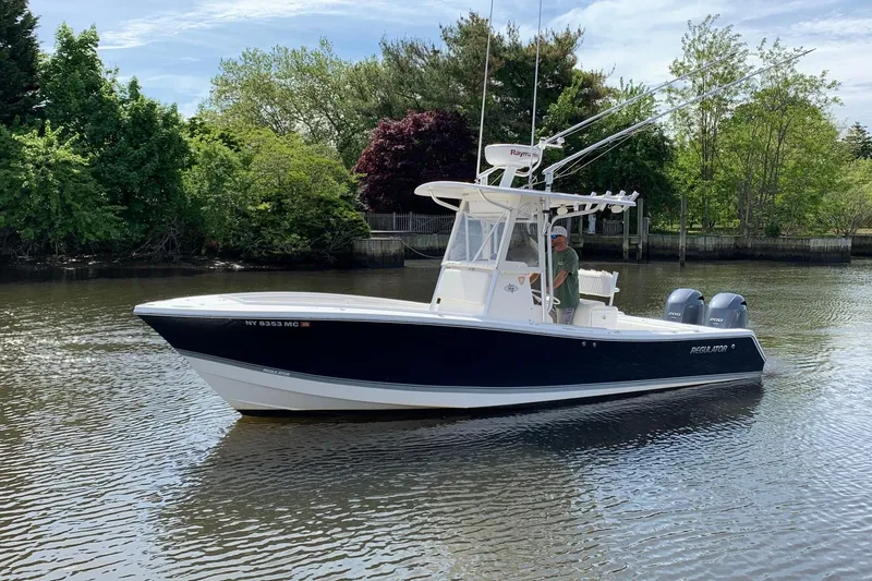 Slide: The Image of 2006 Regulator 24 Classic boat on calm water, surrounded by lush greenery. - 5