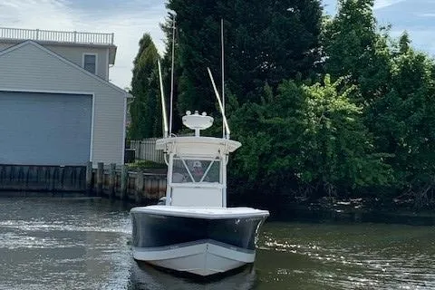 Slide: The Image of 2006 Regulator 24 Classic boat on a calm waterway near trees and a building. - 74