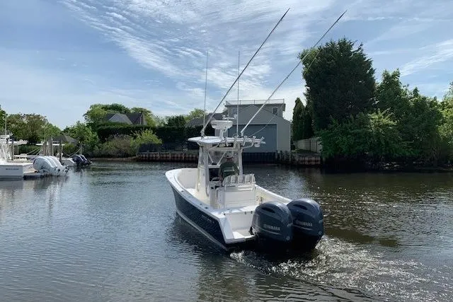 Slide: The Image of 2006 Regulator 24 Classic boat with dual Yamaha engines on a calm waterway. - 75
