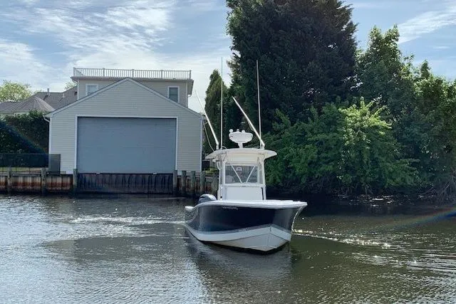 Slide: The Image of 2006 Regulator 24 Classic boat on a calm river near a boathouse and trees. - 77