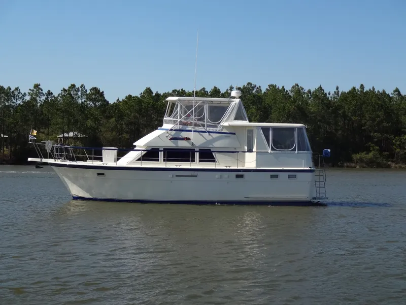 Slide: The Image of 1987 Hatteras 43 yacht on calm water with trees in background. - 1
