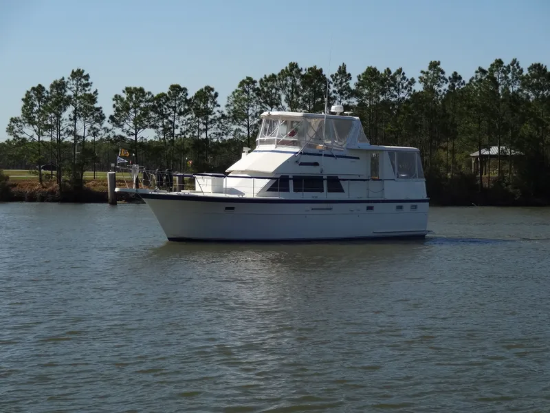 Slide: The Image of 1987 Hatteras 43 yacht on calm water with trees in background. - 11