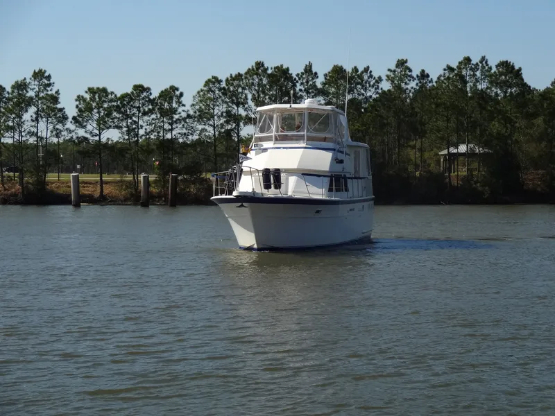 Slide: The Image of 1987 Hatteras 43 yacht cruising on calm water near trees. - 13