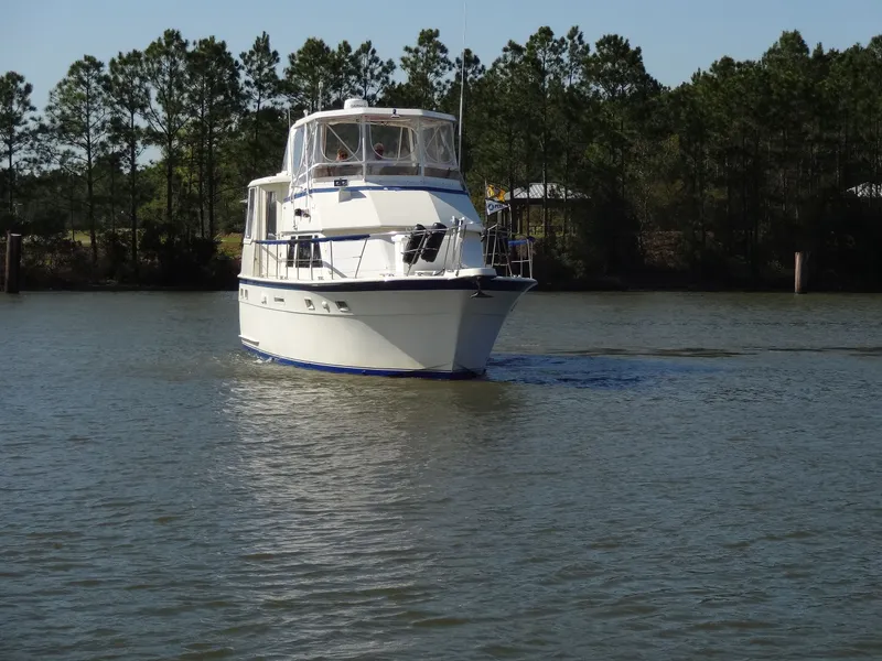Slide: The Image of 1987 Hatteras 43 yacht cruising on calm water near trees. - 14