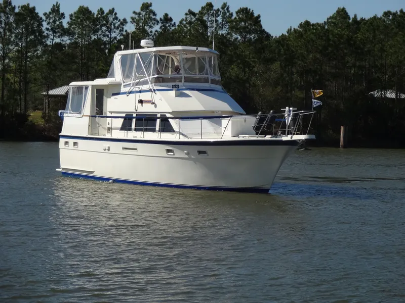 Slide: The Image of 1987 Hatteras 43 yacht on calm water with trees in background. - 15