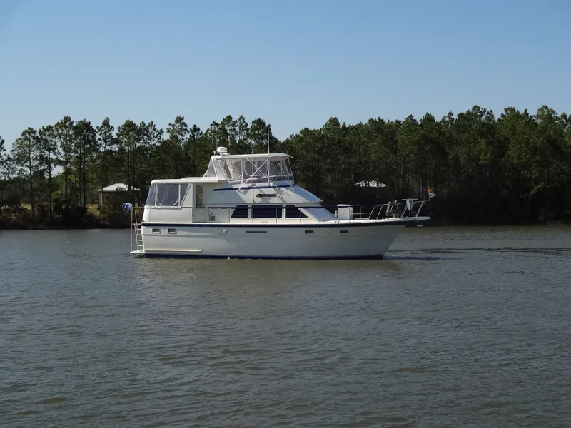 Slide: The Image of 1987 Hatteras 43 yacht on calm water with trees in background. - 16