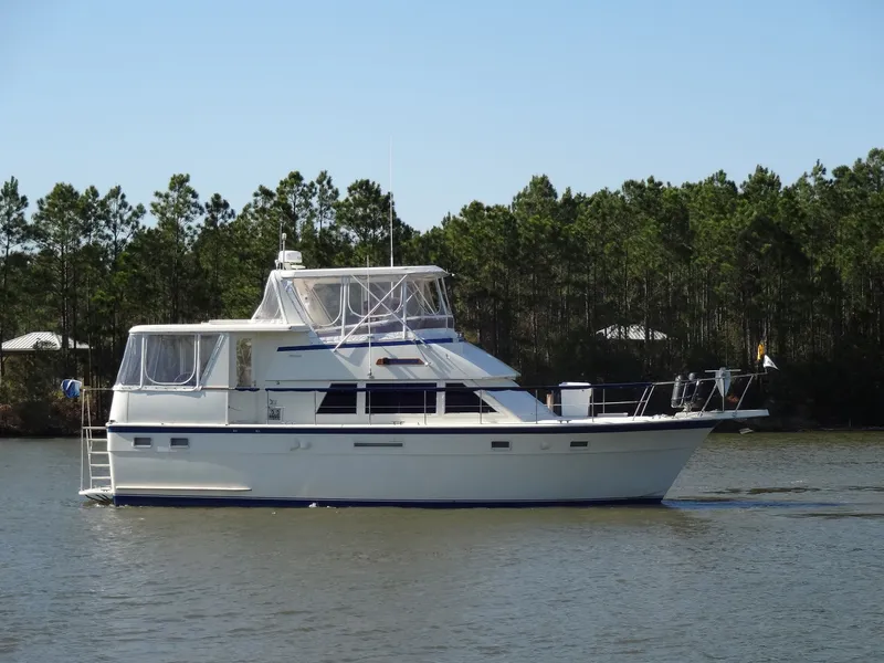 Slide: The Image of 1987 Hatteras 43 yacht on calm water with trees in background. - 17