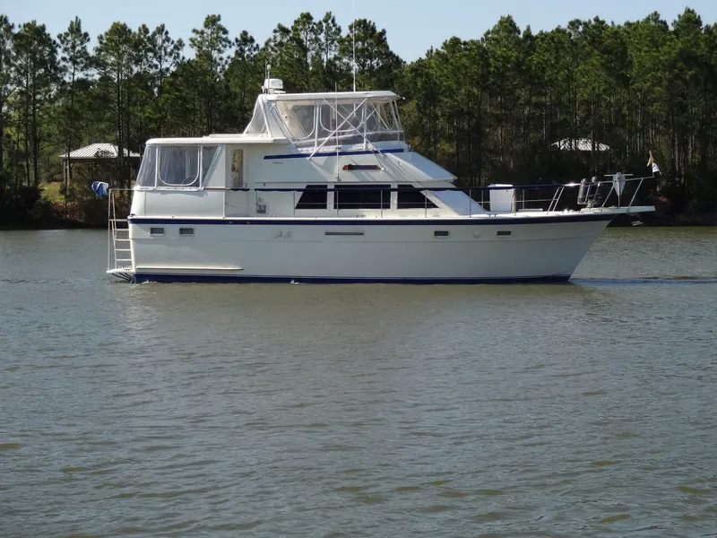 Slide: The Image of 1987 Hatteras 43 yacht on calm water with trees in background. - 18