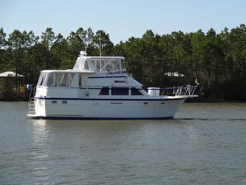 Slide: The Image of 1987 Hatteras 43 yacht on calm water with trees in background. - 20