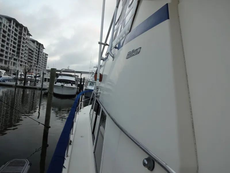 Slide: The Image of 1987 Hatteras 43 yacht docked near modern buildings. - 25