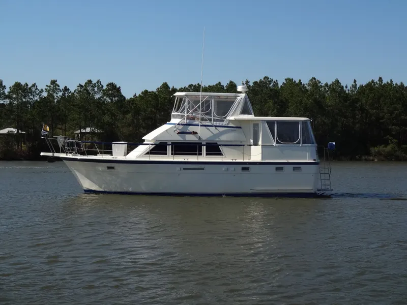 Slide: The Image of 1987 Hatteras 43 yacht on calm water with trees in background. - 7
