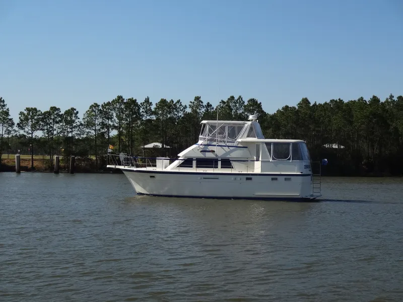 Slide: The Image of 1987 Hatteras 43 yacht on calm water with trees in background. - 9