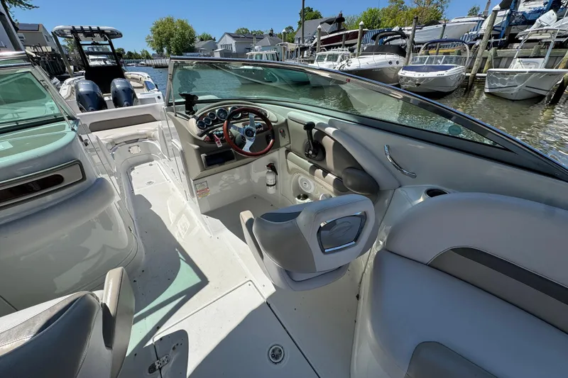 Slide: The Image of 2013 Crownline Eclipse E6 XS boat interior with steering wheel and seating at a marina. - 10