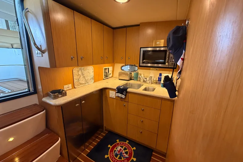 Slide: The Image of 2002 Tiara Yachts 3800 Open galley with wood cabinetry, microwave, and sink. - 17