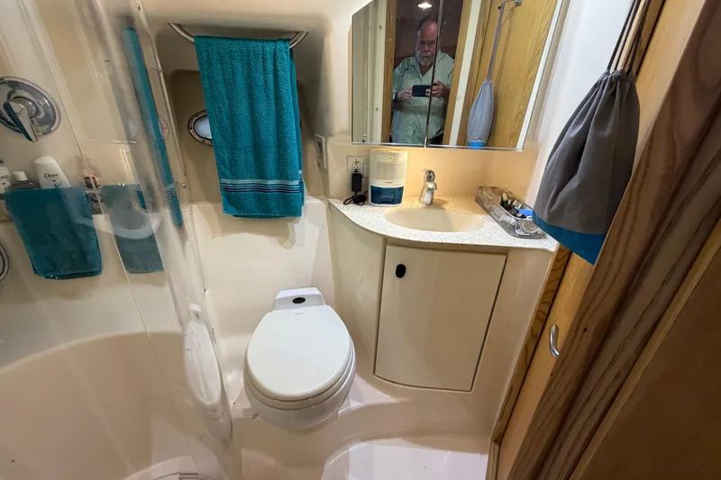 Slide: The Image of Bathroom interior of 2002 Tiara Yachts 3800 Open, featuring toilet, sink, and teal towels. - 18