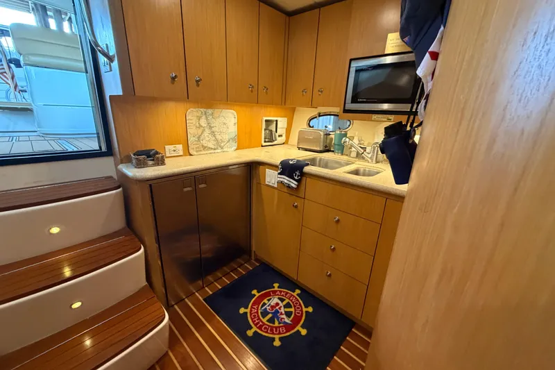 Slide: The Image of 2002 Tiara Yachts 3800 Open galley with wood cabinetry, microwave, and nautical decor. - 26