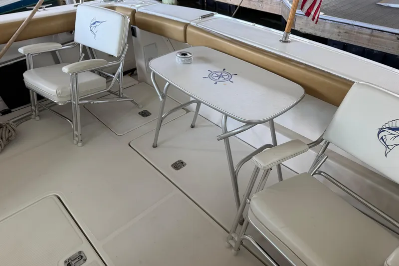 Slide: The Image of 2002 Tiara Yachts 3800 Open cockpit with chairs and table, featuring nautical designs. - 6