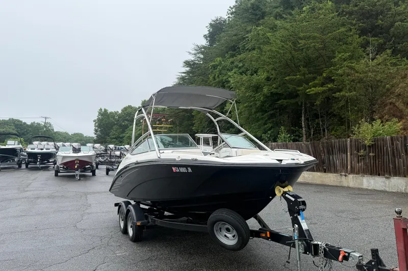 Slide: The Image of 2013 Yamaha AR210 boat on trailer in a parking lot, surrounded by trees. - 1