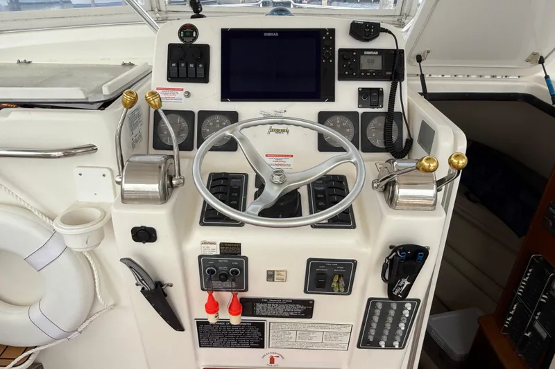 Slide: The Image of Helm of 2001 Pursuit 3000 Offshore boat with steering wheel and navigation controls. - 16