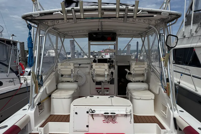 Slide: The Image of 2001 Pursuit 3000 Offshore boat interior with seating and fishing equipment at a marina. - 2
