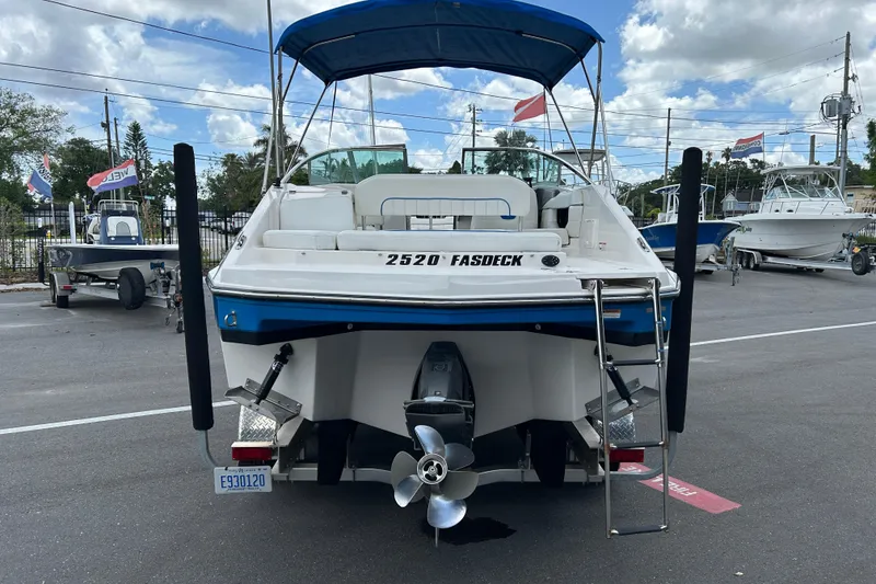 Slide: The Image of 2008 Regal 2520 FasDeck boat with blue canopy, parked on a lot under cloudy skies. - 3