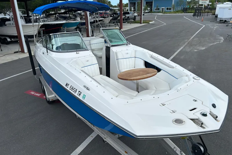 Slide: The Image of 2008 Regal 2520 FasDeck boat with blue hull, white interior, and wooden table on trailer. - 6