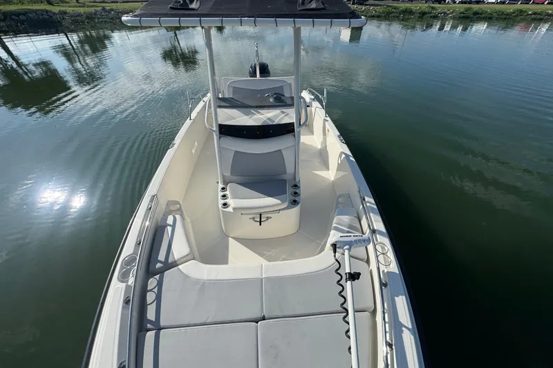 Slide: The Image of 2014 Boston Whaler 210 Dauntless boat on calm water, featuring spacious deck and seating. - 14