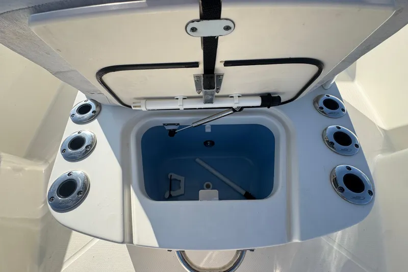 Slide: The Image of Open storage compartment on a 2014 Boston Whaler 210 Dauntless boat, featuring multiple rod holders. - 16