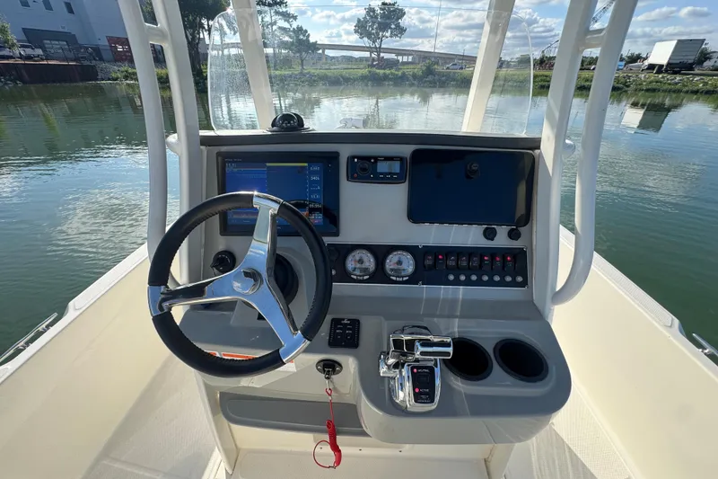 Slide: The Image of 2014 Boston Whaler 210 Dauntless boat console with steering wheel and controls on calm water. - 18
