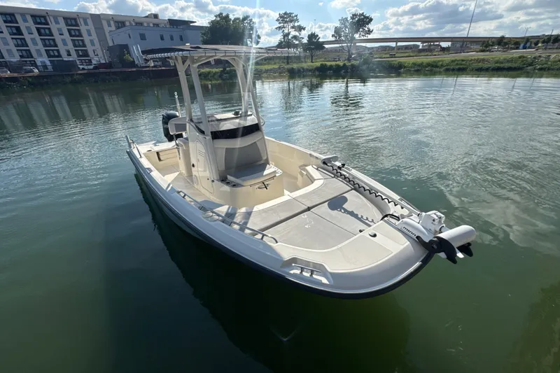 Slide: The Image of 2014 Boston Whaler 210 Dauntless boat on calm water, with modern buildings in the background. - 3