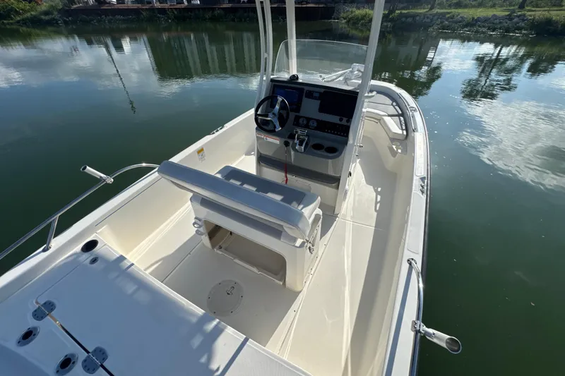Slide: The Image of 2014 Boston Whaler 210 Dauntless boat on calm water, showcasing helm and seating area. - 31