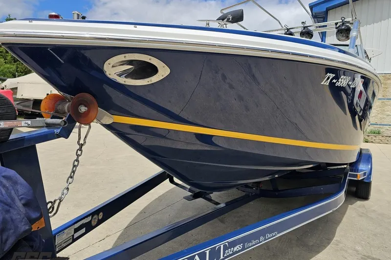 Slide: The Image of 2010 Cobalt 232 WSS boat on trailer, blue hull with yellow stripe, parked outdoors. - 18