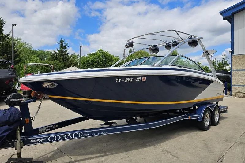 Slide: The Image of 2010 Cobalt 232 WSS boat on trailer, parked outdoors under a partly cloudy sky. - 20