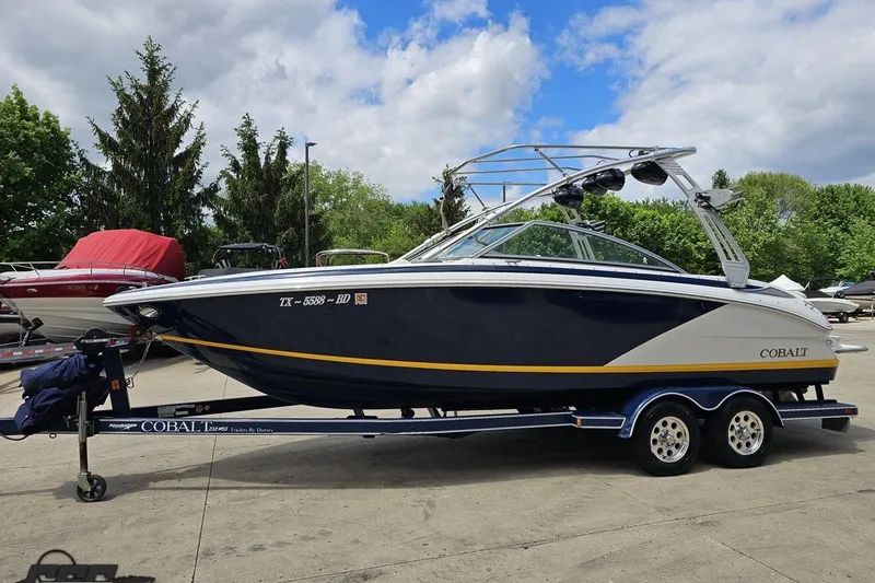Slide: The Image of 2010 Cobalt 232 WSS boat on trailer, parked outdoors under cloudy sky. - 21