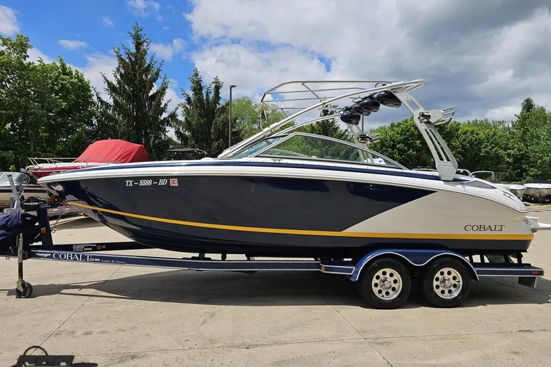 Slide: The Image of 2010 Cobalt 232 WSS boat on trailer, parked outdoors under a partly cloudy sky. - 22
