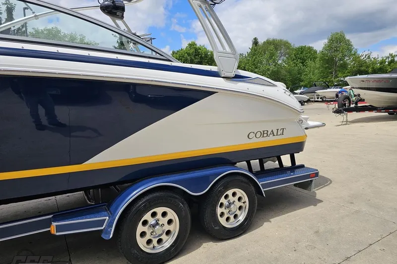 Slide: The Image of 2010 Cobalt 232 WSS boat on trailer, parked outdoors under a partly cloudy sky. - 25