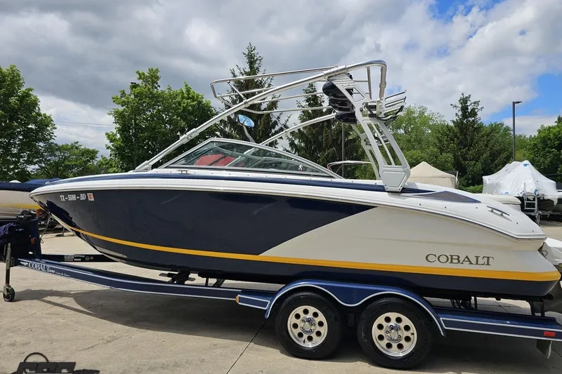 Slide: The Image of 2010 Cobalt 232 WSS boat on trailer, parked outdoors under cloudy sky. - 27