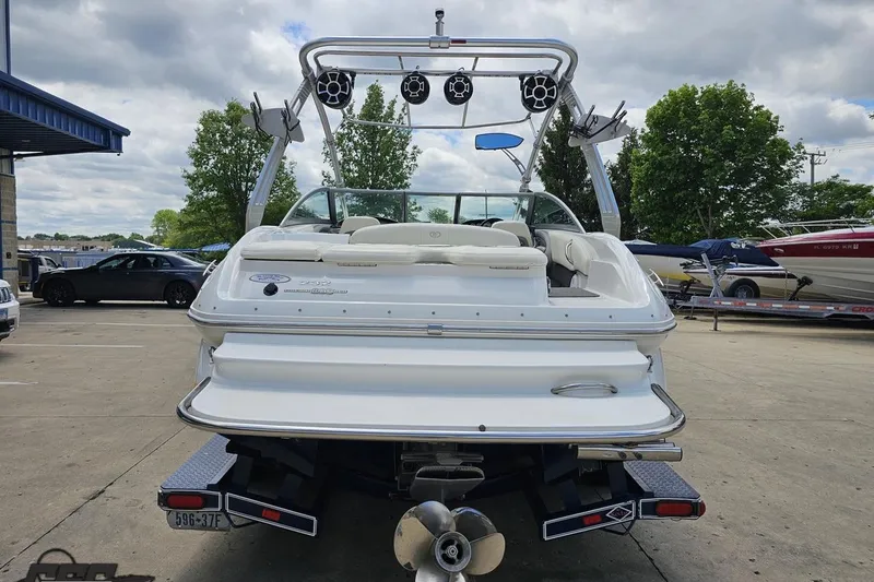 Slide: The Image of 2010 Cobalt 232 WSS boat with wakeboard tower, parked outdoors on a cloudy day. - 32