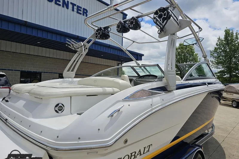 Slide: The Image of 2010 Cobalt 232 WSS boat with tower speakers, parked outside a marine center. - 34