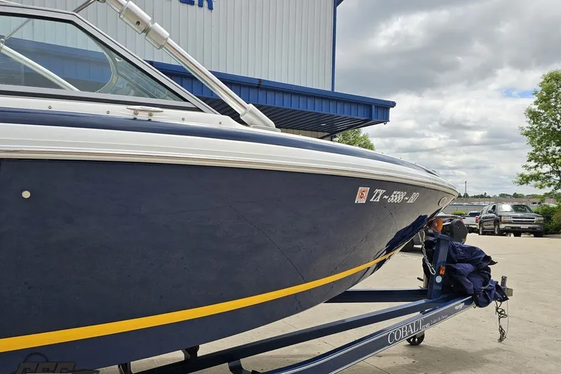 Slide: The Image of 2010 Cobalt 232 WSS boat on trailer, parked outdoors near a building. - 5