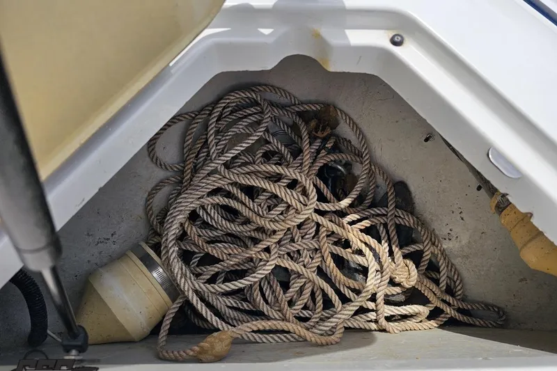 Slide: The Image of Storage compartment of a 2010 Cobalt 232 WSS boat with coiled rope and equipment. - 85