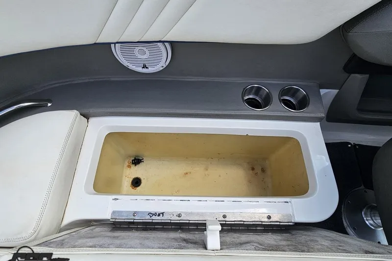 Slide: The Image of Interior of a 2010 Cobalt 232 WSS boat showing storage compartment and cup holders. - 90