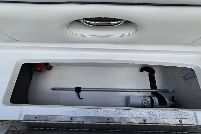 Slide: The Image of Storage compartment in a 2010 Cobalt 232 WSS boat with fire extinguisher and rod. - 92