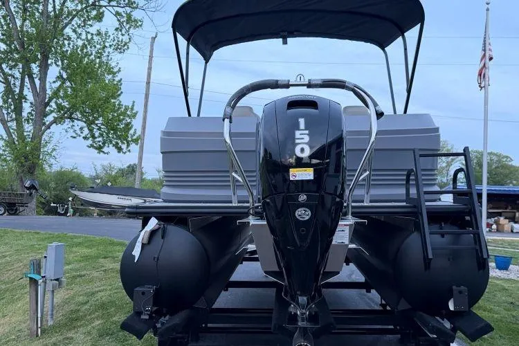 Slide: The Image of 2026 SunChaser Lucerne 22 LR DH Sport pontoon boat with 150 HP engine, parked outdoors. - 2