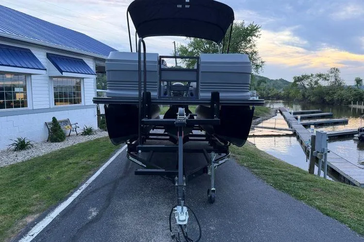 Slide: The Image of 2026 SunChaser Lucerne 22 LR DH Sport pontoon boat on trailer by a lakeside dock. - 3
