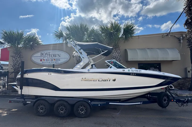 The Image of 2019 MasterCraft X24 boat on trailer at Boat Town dealership, under a sunny sky. - 1