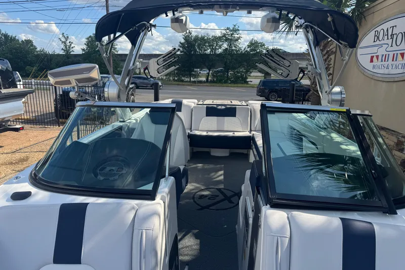 Slide: The Image of 2019 MasterCraft X24 boat interior with seating and wakeboard tower, parked outdoors. - 14