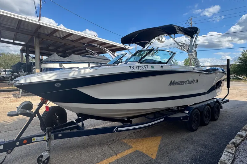 Slide: The Image of 2019 MasterCraft X24 boat on a trailer, parked outdoors under a clear sky. - 3