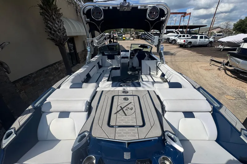 Slide: The Image of 2019 MasterCraft X24 boat with spacious seating and modern design, parked outdoors. - 6